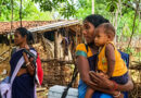 Balancing motherhood and public service, an ASHA worker carried her child in her arms while shouldering a polio vaccine box, exemplifying dedication to both her maternal responsibilities and government healthcare duties.