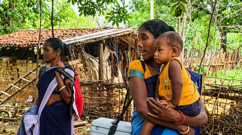 Balancing motherhood and public service, an ASHA worker carried her child in her arms while shouldering a polio vaccine box, exemplifying dedication to both her maternal responsibilities and government healthcare duties.